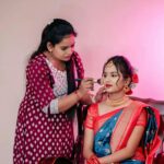 Bride in traditional attire getting makeup done before wedding ceremony.